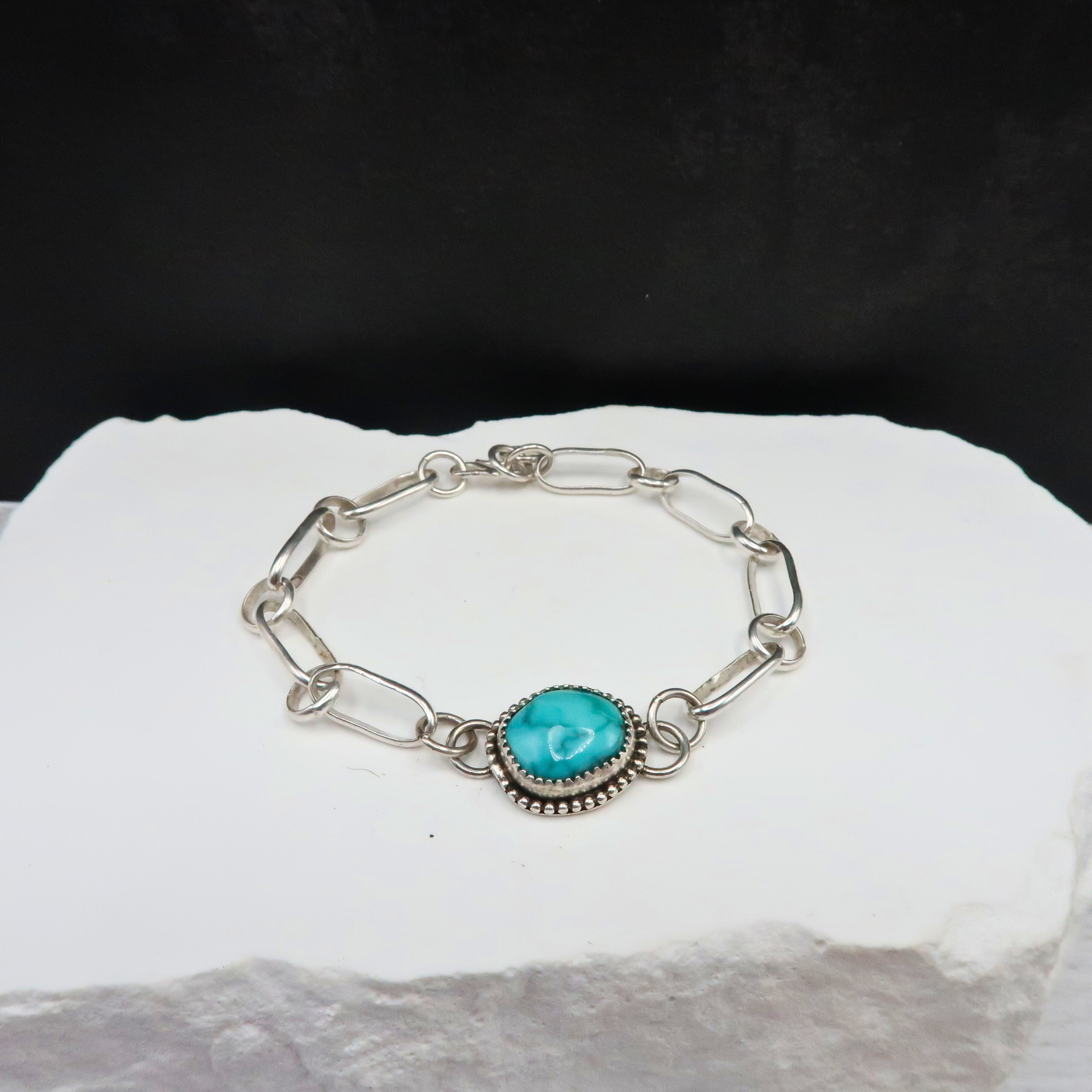 Silver bracelet with a turquoise stone on a white surface