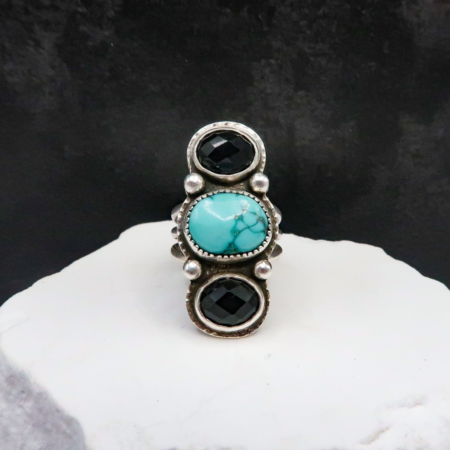 Large Ring with turquoise and black stones on a white surface