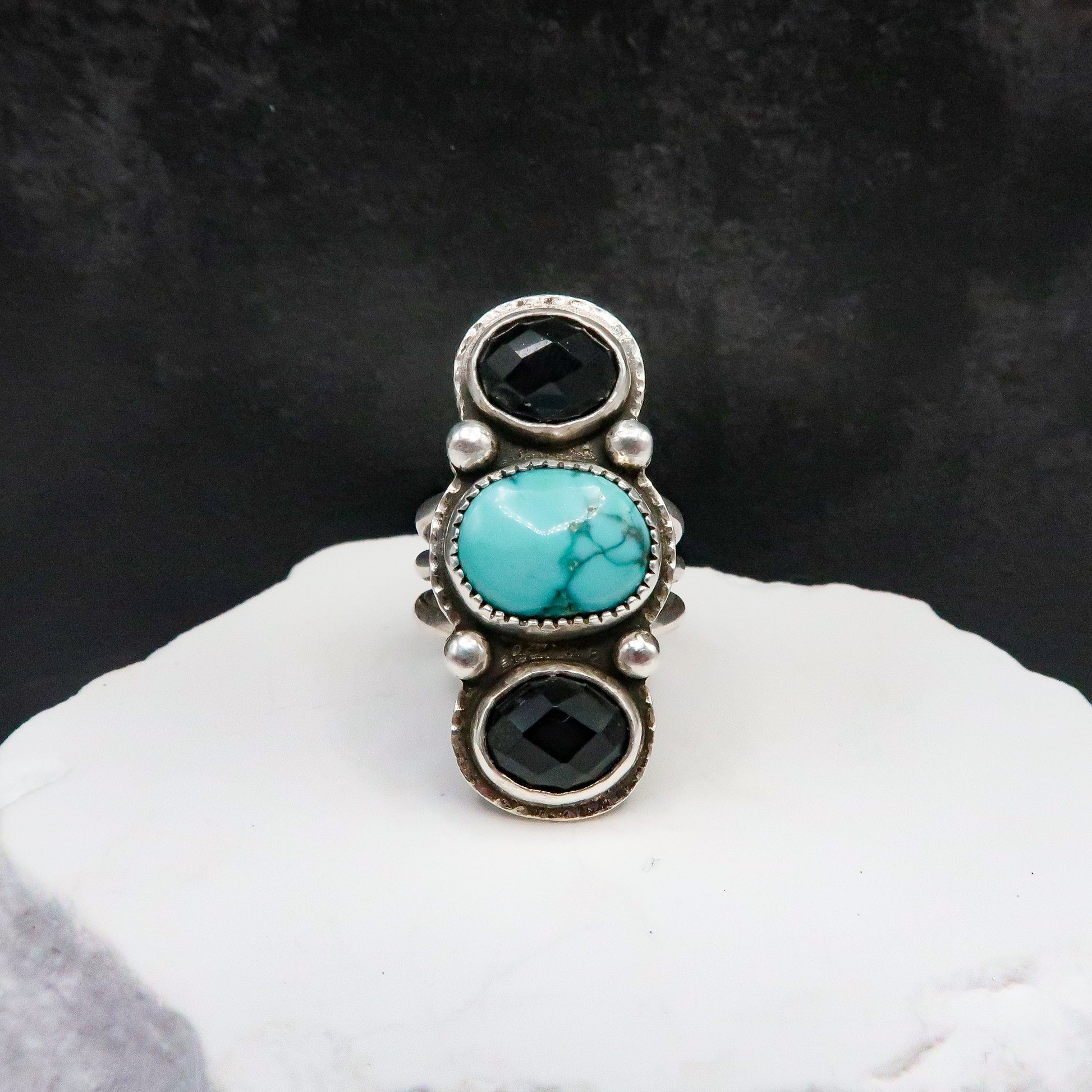 Large Ring with turquoise and black stones on a white surface