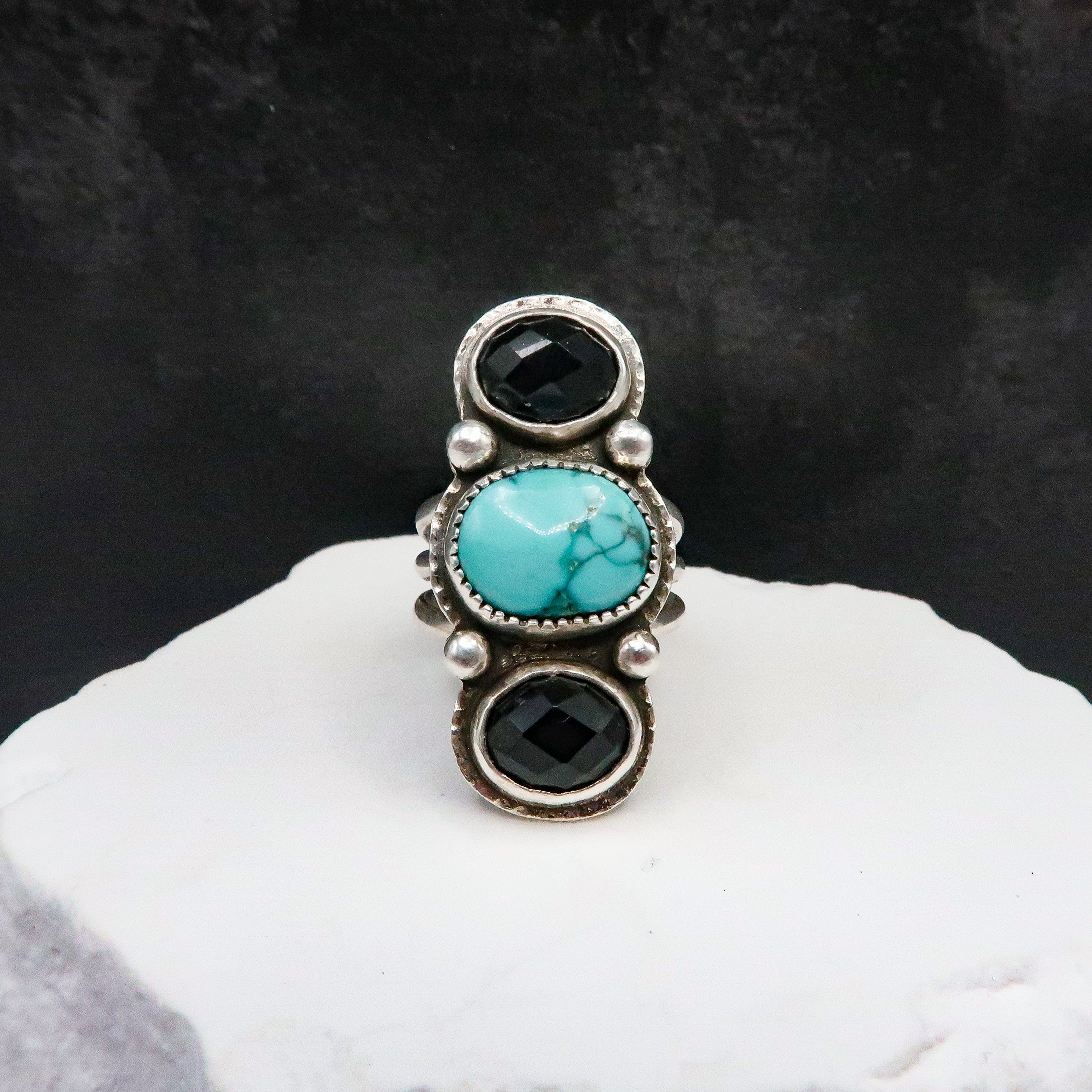 Large Ring with turquoise and black stones on a white surface