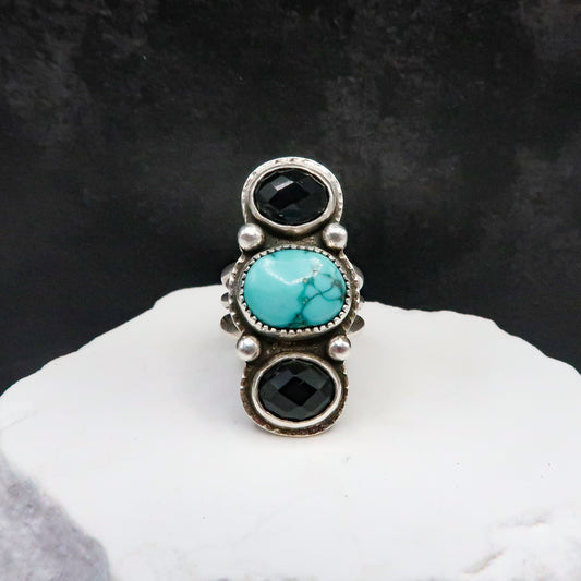 Large Ring with turquoise and black stones on a white surface